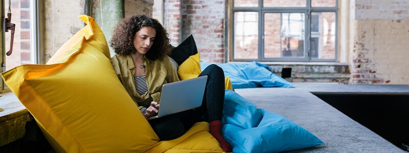 Woman sits on a pillow while exploring social media. 