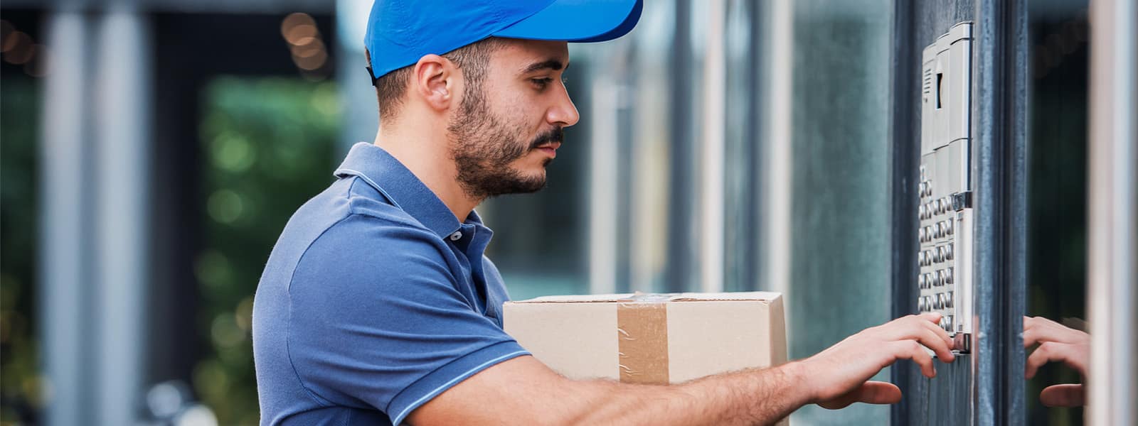 A delivery man with a blue hat and shirt delivering a package