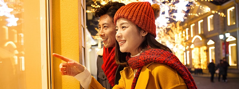 An Asian couple window shops to illustrate how holiday activity can distract at a time when cybercrimes occur. 