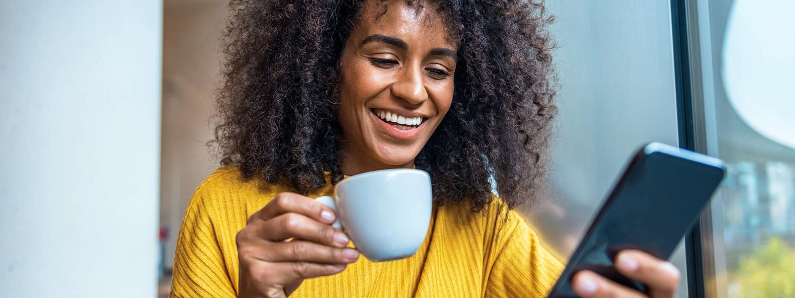 A Black woman enjoys her morning coffee as she learns how to protect personal information online. 