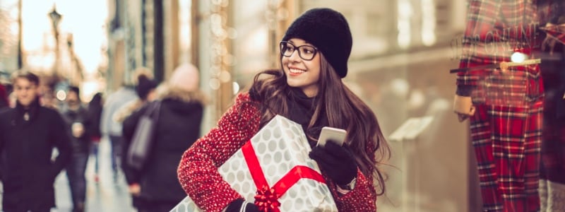 Woman carrying present and smart phone