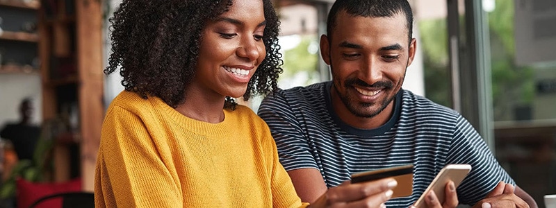 A Black couple reviews their mobile purchase to make sure they aren’t falling for any online scams. 